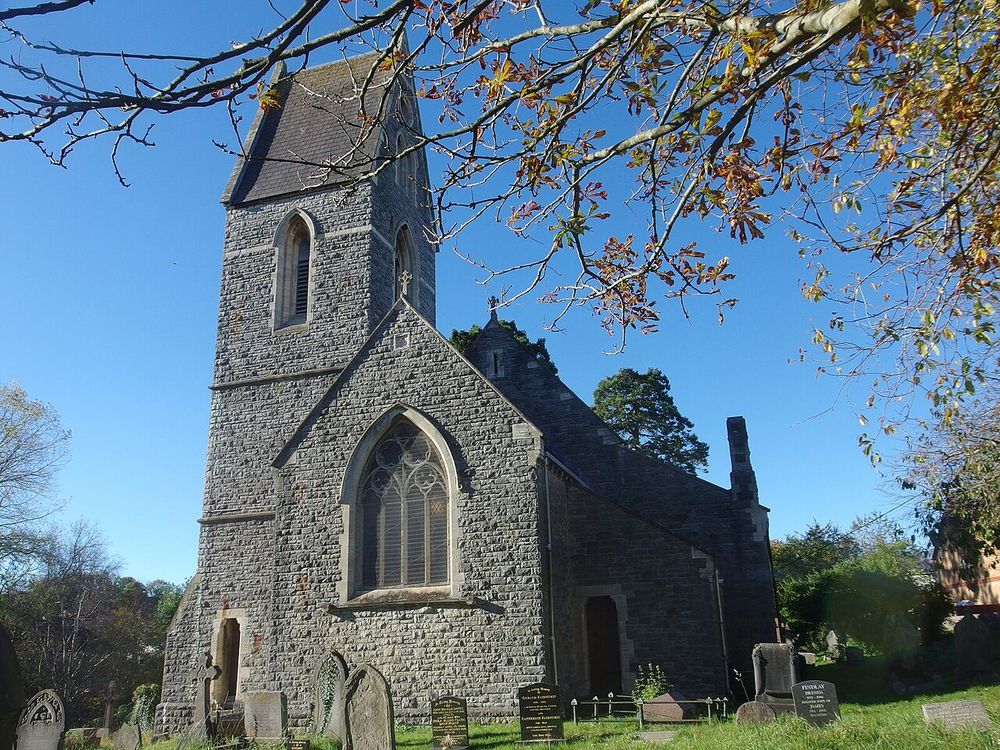 St Dochdwy's Church, Llandough, a stone church with a spire, seen across the churchyard.